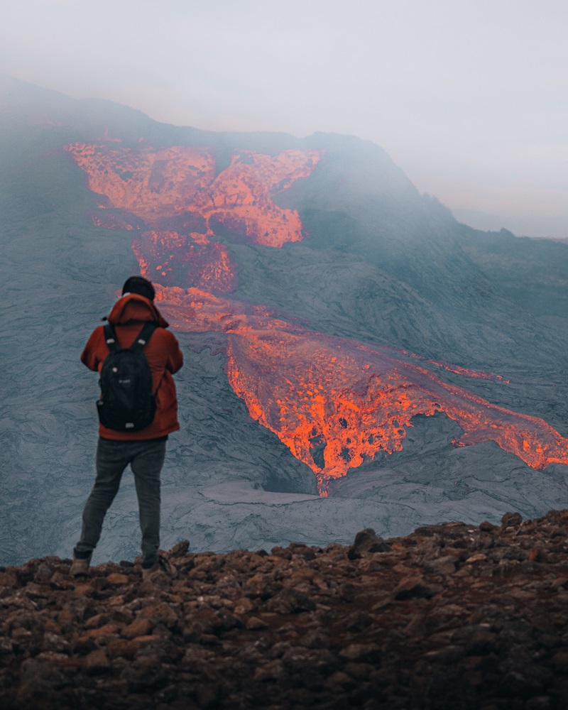 a person standing in front of a erupting volcano in Reykjanes 